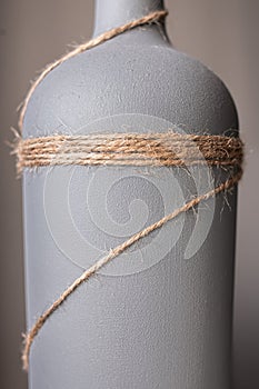 A wine bottle painted gray and decorated with jute rope