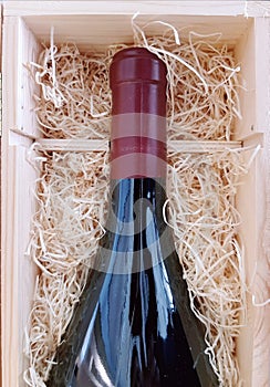 Wine bottle presented in a wooden box and sawdust