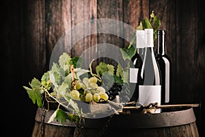 Wine. Bottle of red wine with ripe grapes over wooden background