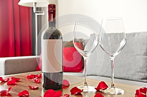 Wine bottle, two glasses and rose petals on a table - romantic a