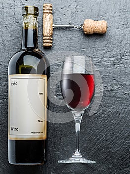 Wine bottle, wine glass and corkscrew on the graphite board.