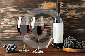 Wine bottle and wine glass with grapes on brown wooden background