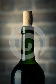Wine bottle on a wooden table with bricks wall background close