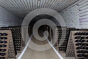 Wine bottles are aged in dark cellar or basement. Background