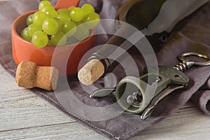 Wine bottles, glass, corkscrew, grapes on table. top view.