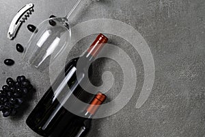 Wine bottles, glass, opener and grapes on concrete background. Copy Space