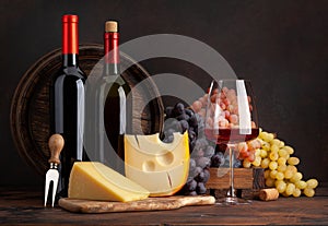 Wine bottles, grapes, cheese, glass of red wine and old barrel