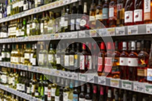 Wine bottles on shelves in a store. Large assortment of alcohol. Blurred