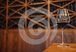 Wine bottles on a wooden shelf. Wine bar. Glass with red wine on wooden background