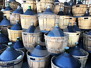 Wine carboys bottles enclosed in wickerwork outside at farm