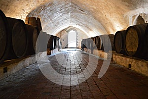 Wine cellar in a medieval castle with old wooden barrels and light coming through the entrance