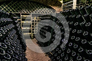 Wine cellar with wine bottles. Old wine bottles covered with dust and cobwebs are in the wine cellar of winery. Alcohol