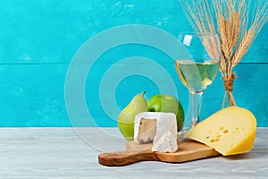 Wine and cheese with fruits on wooden table. Jewish holiday Shavuot