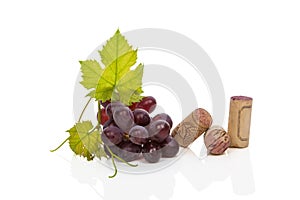 Wine corks, vine leafes and red grapes.