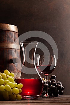 Wine decanter, glass of red wine and old wooden barrel