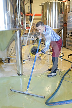 Wine factory worker cleaning floor