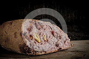 Wine flavoured bread pain au vin with its typical red inside, stuffed with walnuts, on display on a wooden plank