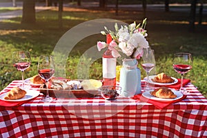 Wine, food and  on picnic table in park on sunny day