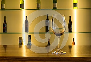 Wine glass against array of bottles