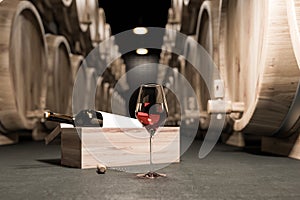 Wine glass and bottle on dark wine cellar floor