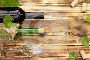 Wine glass, corkscrew, corks, wine bottles, grapevine on rustic burnt wooden background. Top view. Copy space