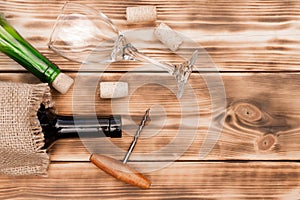 Wine glass, corkscrew, corks, wine bottles, grapevine on rustic burnt wooden background. Top view. Copy space