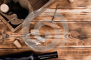 Wine glass, corkscrew, corks, wine bottles, grapevine on rustic burnt wooden background. Top view. Copy space