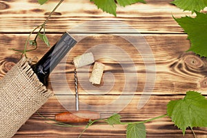 Wine glass, corkscrew, corks, wine bottles, grapevine on rustic burnt wooden background. Top view. Copy space