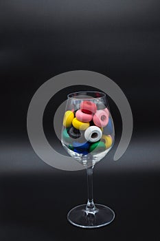 Wine glass filled with wooden circles of many colors