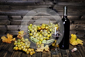 Wine glass and fresh bunch of white grapes on antique wooden background.