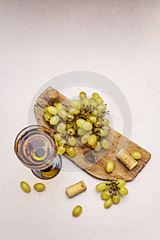 Wine glass, fresh grapes and corks on wooden chopping board. Wine bar, winery, wine tasting concept. Stone concrete background photo