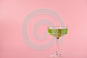 wine glass with green drink on pink background