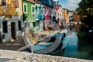 Wine glass of lonely tourist on small bridge in Venice at daytime. Water canals and embankments with historical mansions photo