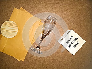Wine Glass Lying Down Between Envelops With A Coaster On Them And A Box On A Particle Board