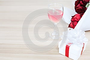 Wine glass put on the wooden table with a gift and red rose, Concept of happiness in giving and receiving gifts from someone