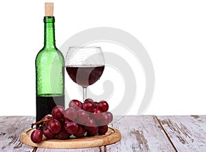 glass with red wine, bottle of wine and grapes isolated over white background