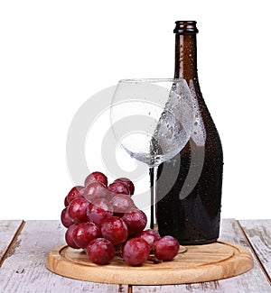 Wine glass with red wine, bottle of wine and grapes isolated over white background