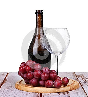 wine glass with red wine, bottle of wine and grapes isolated over white
