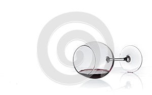 Wine glass with red wine lies on glass on white background
