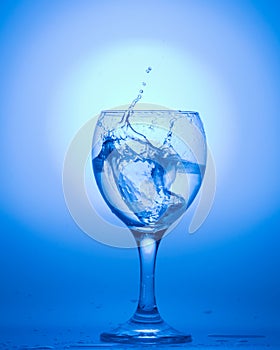 A wine glass with water drops on blue background.