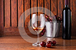 Wine Glass and Wine Bottle with Red Grapes on Wooden Background