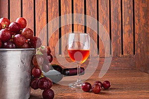 Wine Glass and Wine Bottle with Red Grapes on Wooden Background