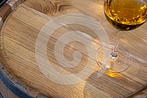 Wine glass with wine on wooden oak barrel. Lid of oak barrel