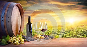 Wine Glasses And Bottle With Barrel In Vineyard photo