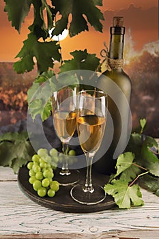 Wine glasses, bunches of grapes on a wooden table, on the background of the sunset