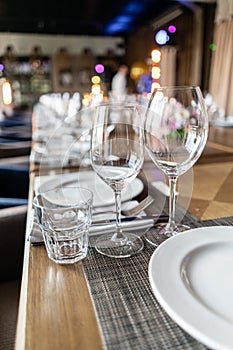 Wine glasses in the foreground. Wedding Banquet or gala dinner. The chairs and table for guests, served with cutlery and