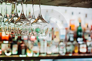 Wine glasses hanging from metal beams on defocused background. S