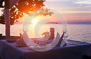 Wine glasses on the table of bar. Sunset over the sea