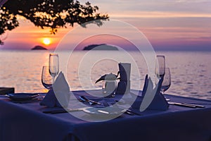 Wine glasses on the table of bar. Sunset over the sea