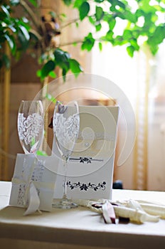 Wine glasses, wedding card with ribbons and an invitation to the table